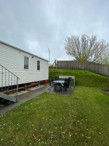 Cross InnDelightful 2 bedroom Caravan, Pencnwc, New Quay的院子里的拖车,带桌椅