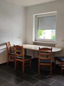 Töging am InnStadthostel的客房设有桌子、两把椅子和窗户。
