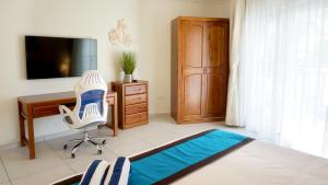 棕榈滩Arena Condominium Aruba的一间卧室配有书桌、椅子和电视。