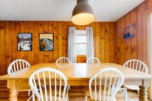 康威Rockhouse Mountain Retreat的一间带木桌和白色椅子的用餐室