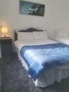 Tory IslandOstán Oileán Thoraí Tory Island Hotel的一间卧室配有一张带蓝色毯子的床
