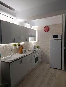 多列毛利诺斯Apartamento Primera Línea de Playa的厨房配有白色家电和墙上的时钟
