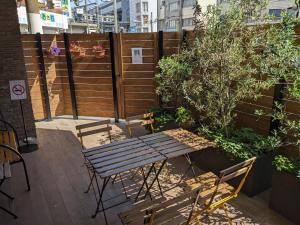 大阪Hostel JIN - Weekly Appartment in Osaka的庭院设有木栅栏和木桌及椅子。