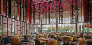 峇六拜槟城国际会展中心阿玛瑞酒店的一间带桌椅和粉红色鲜花的餐厅