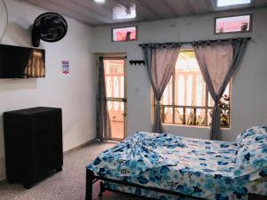 梅尔加GINEZ PRODUCTION COL的一间卧室设有一张床、一台电视和一个窗口。