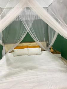 保禄Mon House的卧室配有带白色床单和枕头的天蓬床。