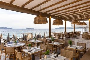 斯基亚索斯镇Skiathos Theros, Philian Hotels and Resorts的海滩上的餐厅,配有桌椅