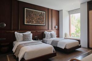 坎古Munno Villa的酒店客房设有两张床,墙上挂有绘画作品