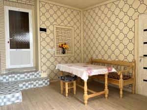 布哈拉Shaxruza Shahzoda Guest House的一间设有桌子、长凳和窗户的房间