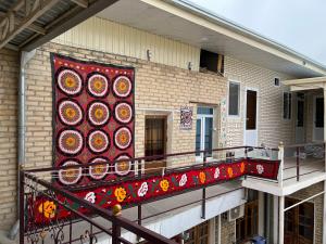 布哈拉Shaxruza Shahzoda Guest House的建筑一侧的阳台,有色彩缤纷的地毯