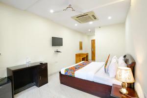 新德里FabHotel F9 NSP的一间卧室配有一张带电视和书桌的床。
