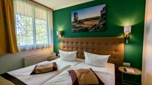 奎德林堡安格鲁 - 奎德林堡酒店的一间卧室设有一张大床和绿色的墙壁