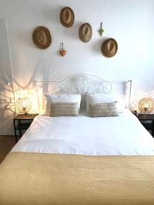 阿尔沃尔Casa Largo do Poço Guesthouse的卧室配有白色床,墙上挂有帽子