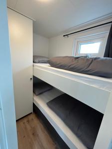 艾默伊登Tiny House in de duinen van IJmuiden aan Zee的一间卧室设有两张双层床和一扇窗户。