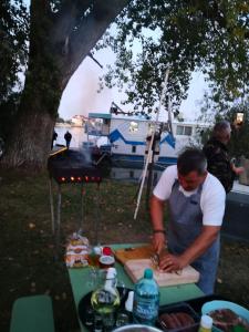 UzlinaHotel plutitor Sofia-Maria的野餐桌上用切板准备食物的人