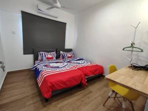 吉隆坡Stay Next to Stadium Axiata Arena Bukit Jalil的一间卧室配有一张带红色毯子和桌子的床。