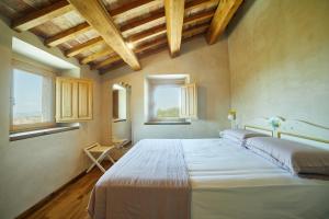 马西尼亚诺Agriturismo Montecolombo by Il Ritorno的一张大床,位于带两个窗户的房间