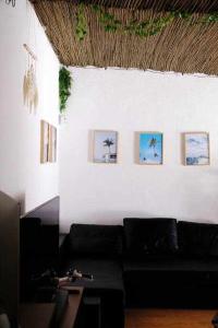 AroeiraSurfie Surf Beach e Adventure的客厅配有黑色沙发和墙上的照片