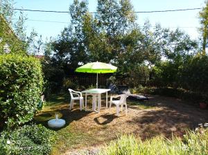 拉贝尔讷里昂雷茨TY BIHAN的院子里的一张桌子和两把椅子以及一把雨伞