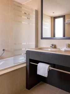 马赛New Hotel of Marseille - Vieux Port的一间带水槽、浴缸和镜子的浴室