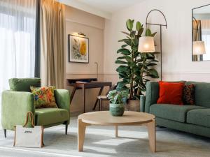 布鲁塞尔布鲁塞尔欧洲索菲特酒店的客厅配有两张绿色椅子和一张桌子