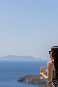 圣罗曼诺斯Kapsalos Villas的穿着泳衣的女人,拿着一杯葡萄酒
