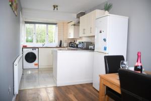 沃尔索尔2ndHomeStays -Willenhall-Charming 3-Bedroom Home的厨房配有白色橱柜和白色冰箱。