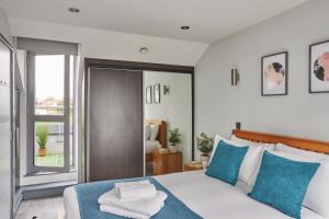 伦敦Wembley Stadium by Viridian Apartments的一间卧室配有一张带蓝色和白色枕头的床