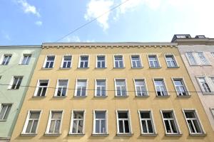维也纳Vienna Palm Apartments的街道上一座黄色建筑,设有白色窗户