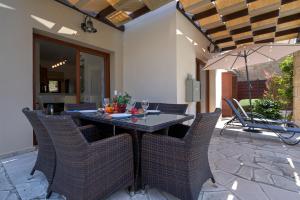 库克里亚3 bedroom Villa Athina with private pool and golf views, Aphrodite Hills Resort的庭院里配有桌椅和遮阳伞