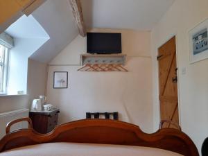 LuckingtonCotswold Cottage Bed & Breakfast的卧室配有一张床,墙上配有电视。