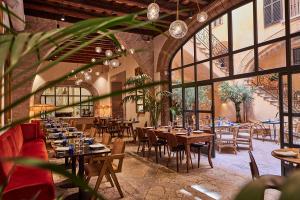 马略卡岛帕尔马Puro Grand Hotel的餐厅设有木桌、椅子和窗户。