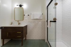 奥克兰Signature Inn Oakland的一间带水槽、镜子和淋浴的浴室