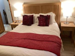 朗德斯通Abby's Cottage Roundstoneselfcatering的一张大床,配有红色和白色的床单和枕头