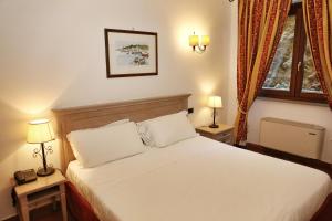 圣托斯特凡诺港Mercure Argentario Hotel Filippo II的一间卧室配有一张带两盏灯的床和一扇窗户。