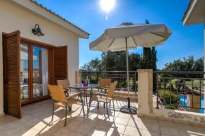 库克里亚2 bedroom Villa Proteus with private pool, Aphrodite Hills Resort的庭院配有桌椅和遮阳伞。