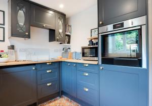3 Pond Cottages的厨房配有蓝色橱柜和微波炉