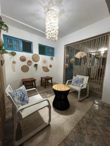 费尔南多 - 迪诺罗尼亚Pousada Sette Mares的客厅配有椅子、桌子和吊灯。