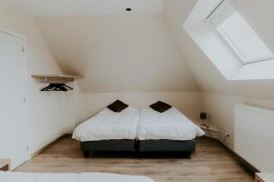 WingeneLuxe Vakantiewoning De Veldhoek的阁楼卧室配有2张带白色床单的床