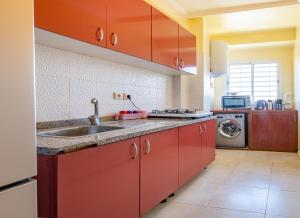 马拉喀什Appartement 2 chambre 5min Aéroport的一间带红色橱柜和水槽的厨房
