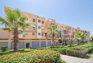 马拉喀什Appartement 2 chambre 5min Aéroport的一排公寓楼,有棕榈树和灌木