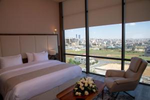 安曼Jeddah Homes Boutique Hotel的一间卧室配有一张床、一把椅子和窗户。