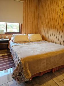 瓦尔迪维亚Cabañas Rosner的木墙客房的一张床位