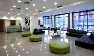 莱约阿NH拉阿旺萨达酒店的大型大堂配有沙发、椅子和窗户。