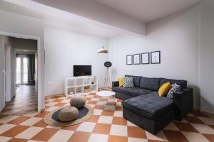 MoíraiHospitium Crete的客厅配有黑色沙发和 ⁇ 格地板