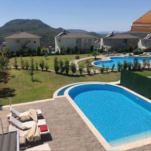 CeditVacation home with private pool, Fethiye, Oludeniz的一个带椅子的庭院和房子的游泳池