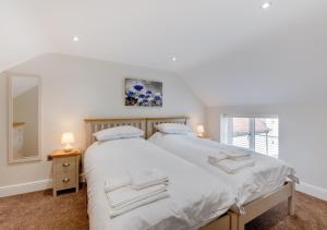 BrisleyLillie Cottage的一间卧室配有一张带白色床单和镜子的床
