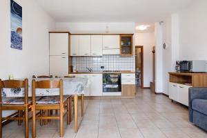 布雷佐内加尔达Appartamento Assenza 9的厨房配有白色橱柜和桌椅