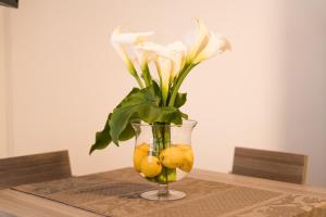 加利波利Sunset home Baia Blu的花瓶,桌子上放着花和柠檬