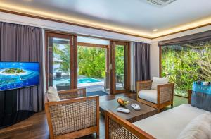 希曼杜岛马尔代夫坎德鲁度假酒店的客厅配有电视和桌椅